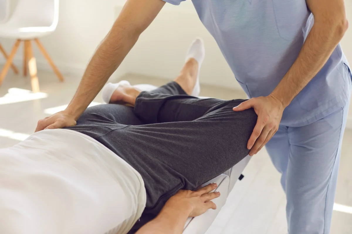 Osteopata wykonuje terapię manualną biodra podczas zabiegu pacjenta