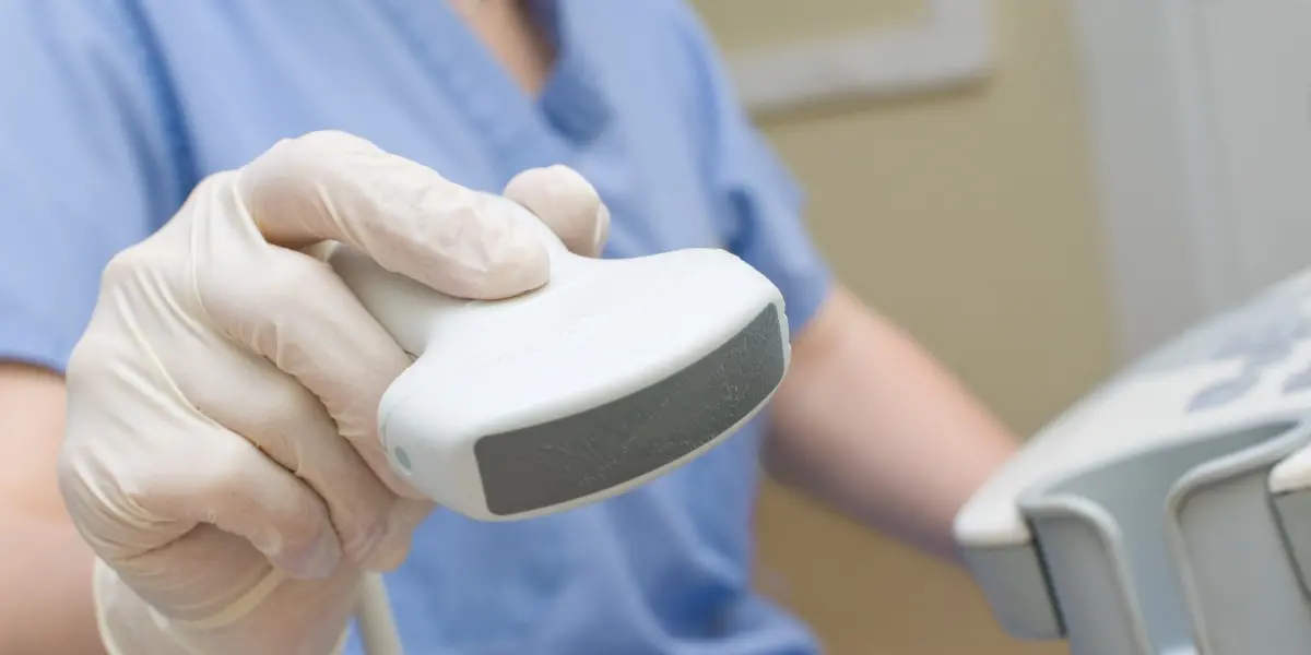 Zbliżenie na głowice do USG, którą w ręce trzyma diagnosta lub lekarz.